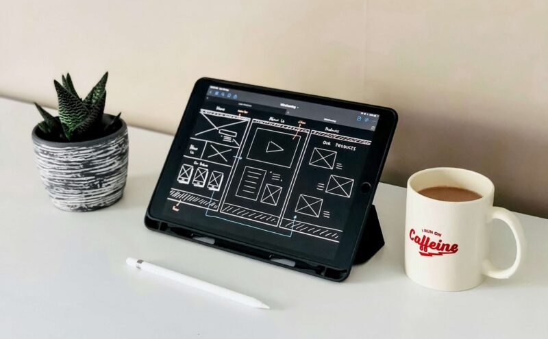 black ipad beside white ceramic mug on white table